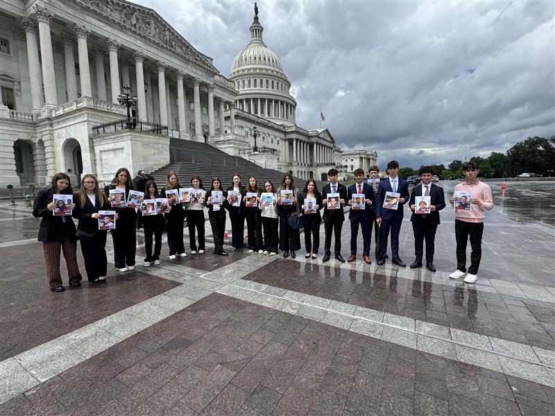 Teen leaders from TILC's junior class stand in front of the White House holding photos of the hostages.