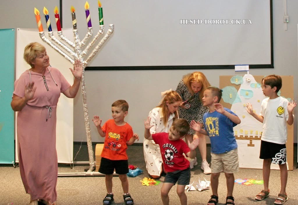 Children dance around a menorah in Cherkassy's Family Camp